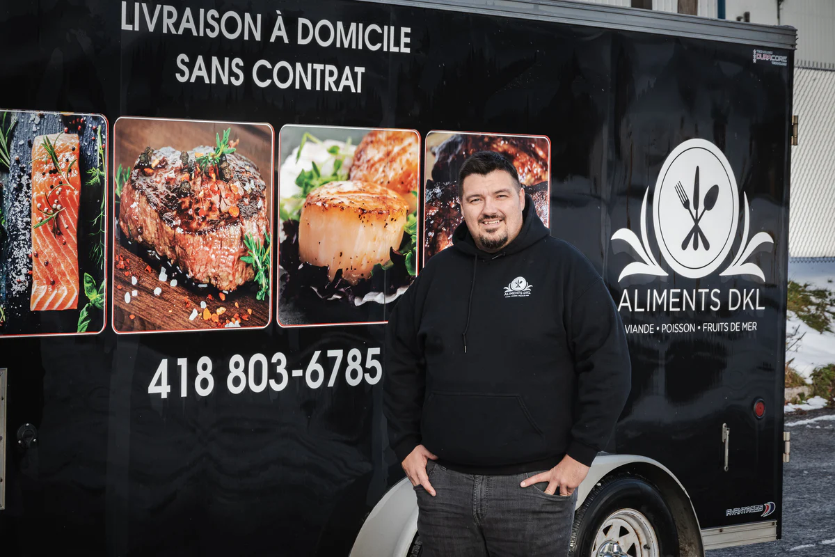 Camion de livraison Aliments DKL avec son fondateur devant le véhicule, spécialisé en livraison de viandes, poissons et fruits de mer surgelés partout au Québec.