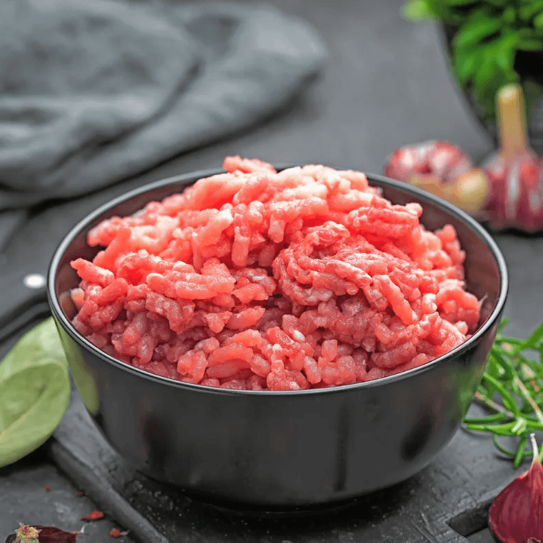 Gros plan sur la texture du porc haché cru aux teintes roses et blanches.