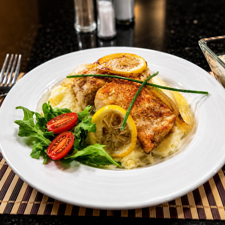 Filet de saumon Atlantique Aliments DKL en cuisson, servi avec légumes grillés et quartiers de citron. Saumon sans peau de qualité supérieure, offert en boîte de 2 kg, idéal pour le four, le BBQ ou la friteuse à air.